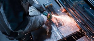 A man using an angle grinder on a piece of steel