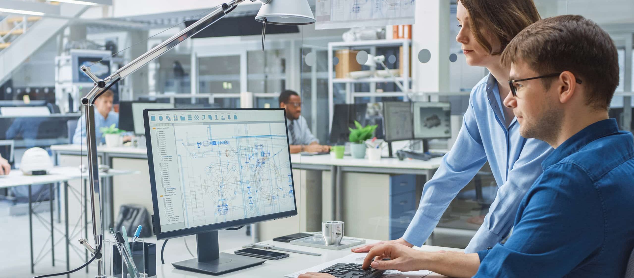 Employees reviewing drawings on a computer monitor